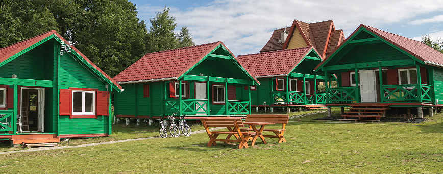 drewniane domy letniskowe pomalowane na zielono, na campingu